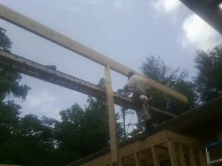 Carpenter setting a ridge beam over a new addition frame — Ice Dam Removal by Roofing Brothers in Cedar Grove