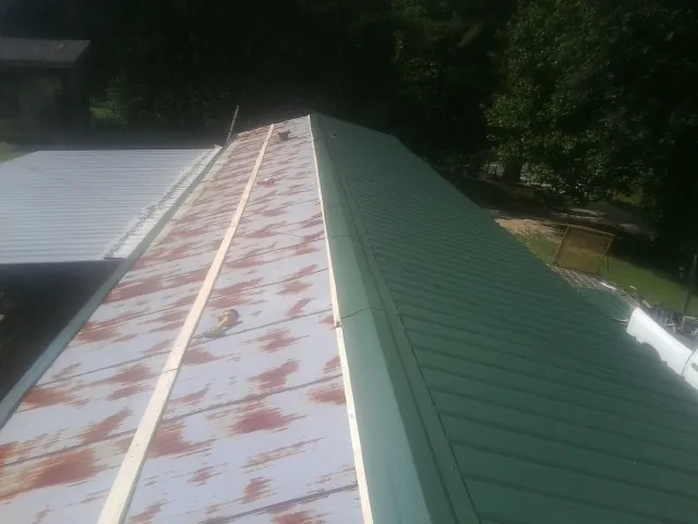 Old rusted panels beside newly installed green metal roofing — Wind Damage Roof Repair by Roofing Brothers in Cedar Grove